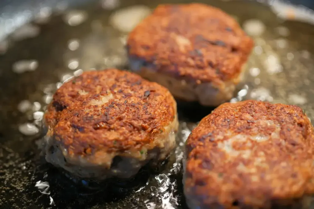 Traditional meatballs sizzling in a skillet with a golden-brown crust.