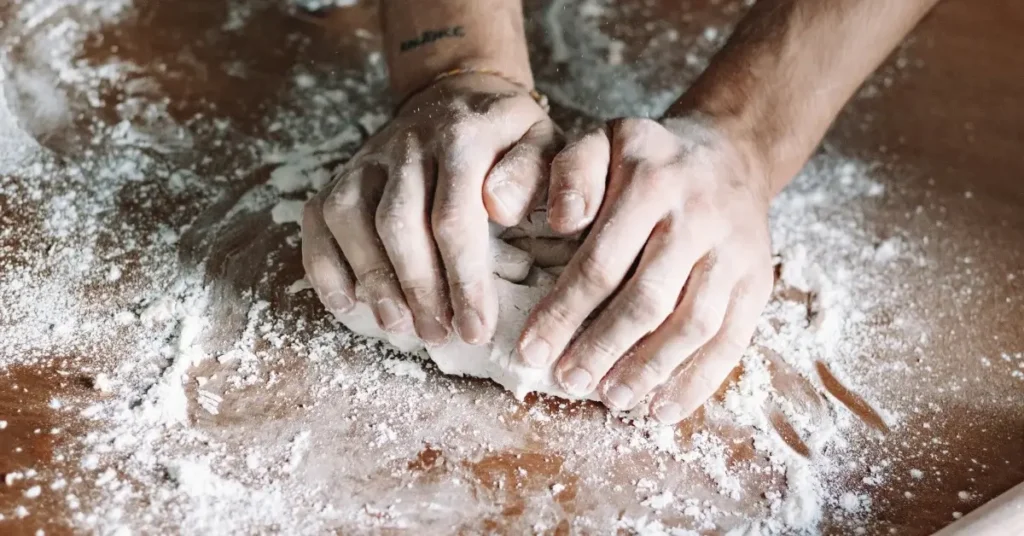 Hands kneading sourdough on a floured surface