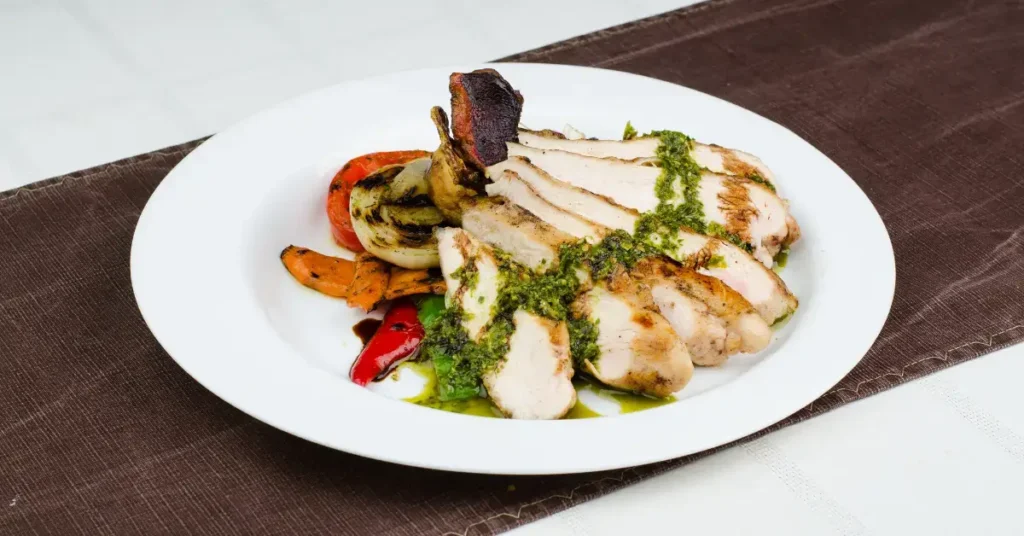 Gourmet plated thin sliced chicken breast with a colorful salad, roasted vegetables, and quinoa, styled for a balanced meal.